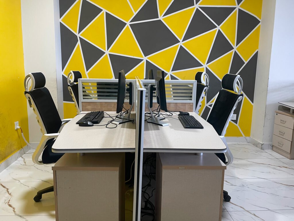 A desk with 4 persons sitting capacity equipped with 4 personal computers.